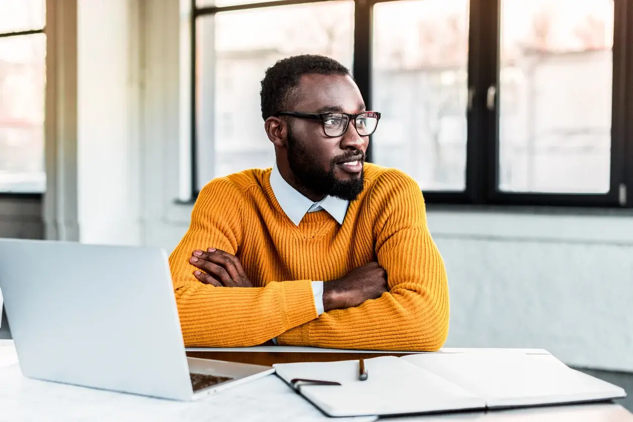 Man in an orange sweater sitting at a desk