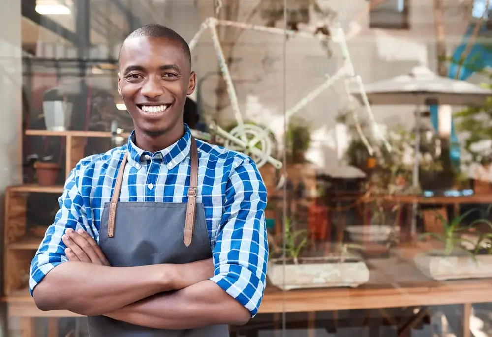 Man standing in an apron with his arms crossed